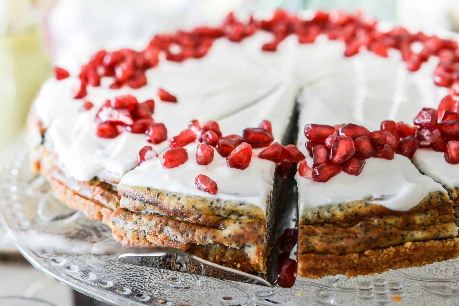 Delicious layered cake with white frosting and pomegranate seeds topping.