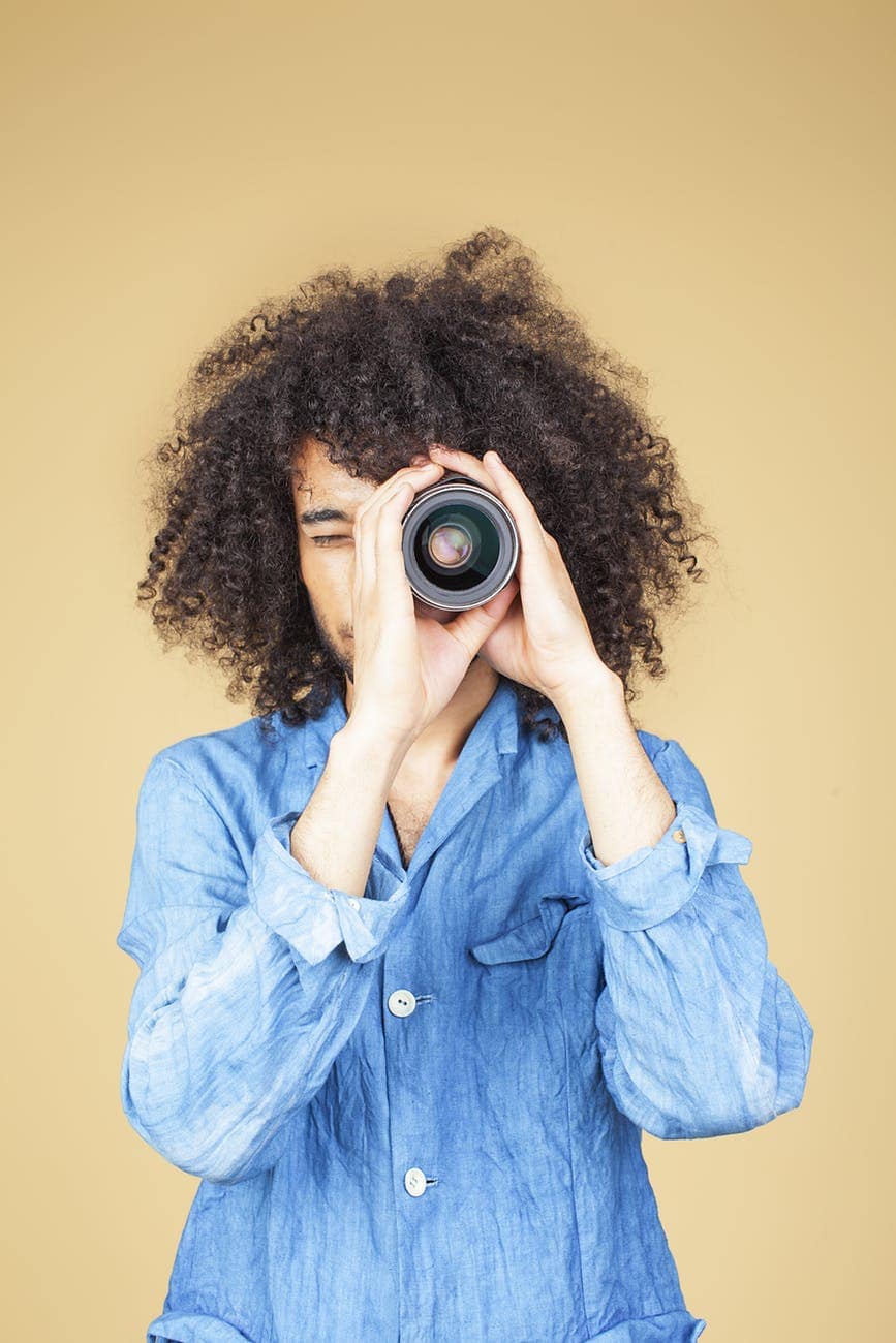 Woman with curly hair taking a photo with a camera, representing conflict resolution and communicati.