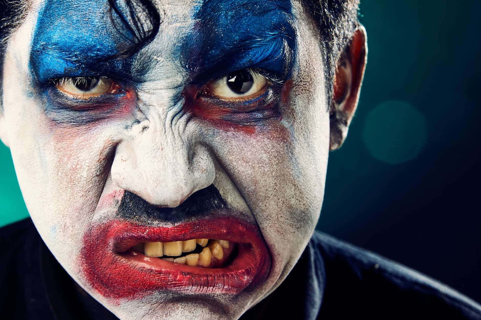 Close-up of an angry clown with makeup and fierce expression.