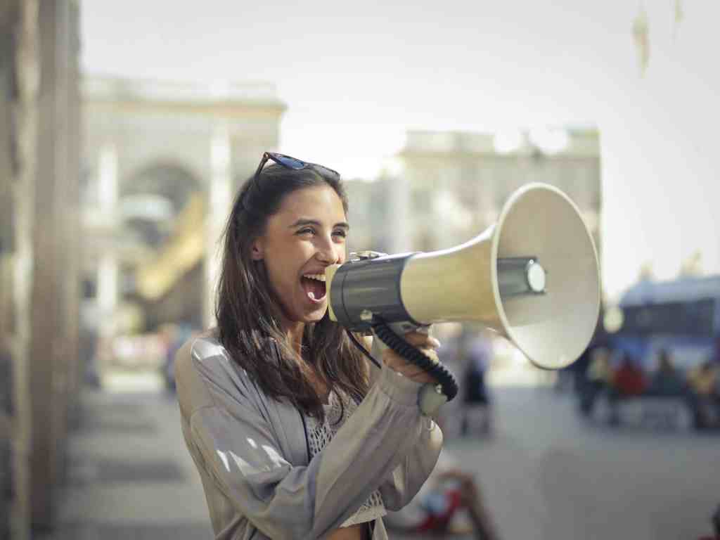 Woman using megaphone to express opinions clearly in a professional setting.