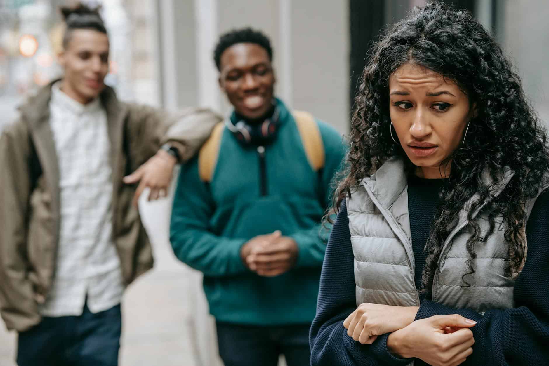 Woman feeling upset as two friends tease her in a conflict situation.