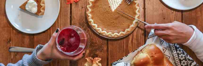 slicing of pumpkin pie placed on wooden surface