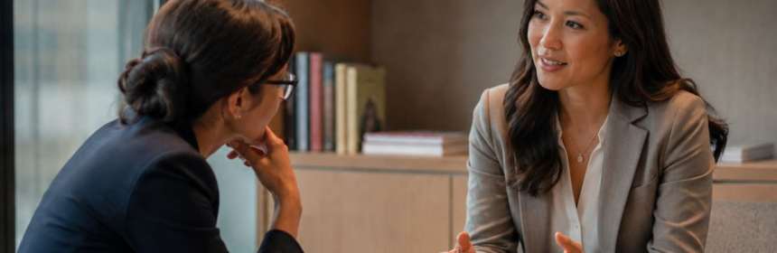 Two colleagues in a calm, private workplace conversation about constructive feedback